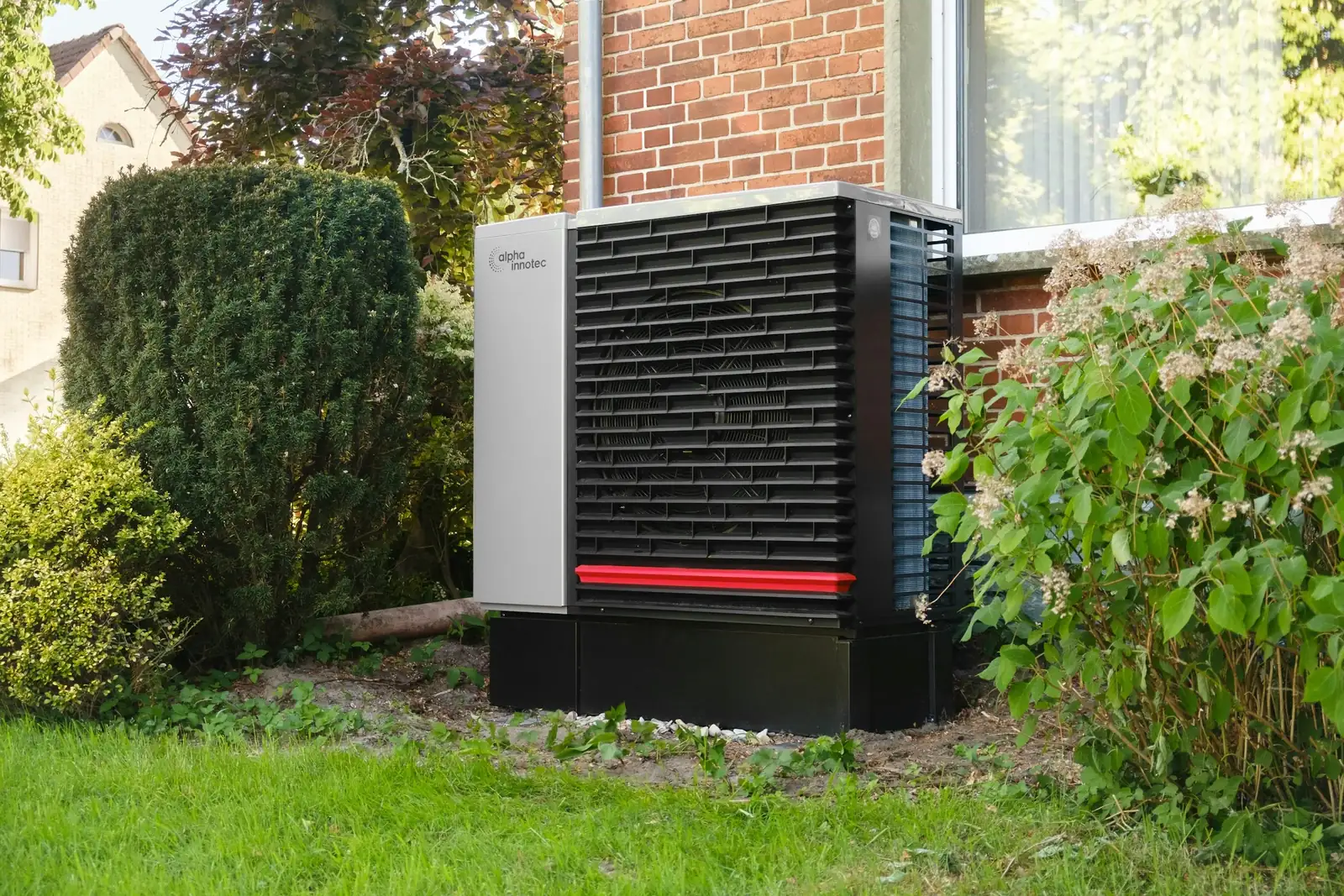 Buitenunit van een warmtepomp naast een bakstenen pand